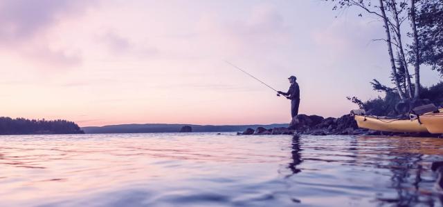 A man fishing against a purple sunset